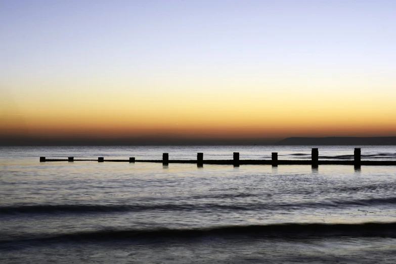 a person riding a surfboard on top of a body of water, by Julian Allen, minimalism, sunset panorama, lined up horizontally, rails, 5 5 mm photo