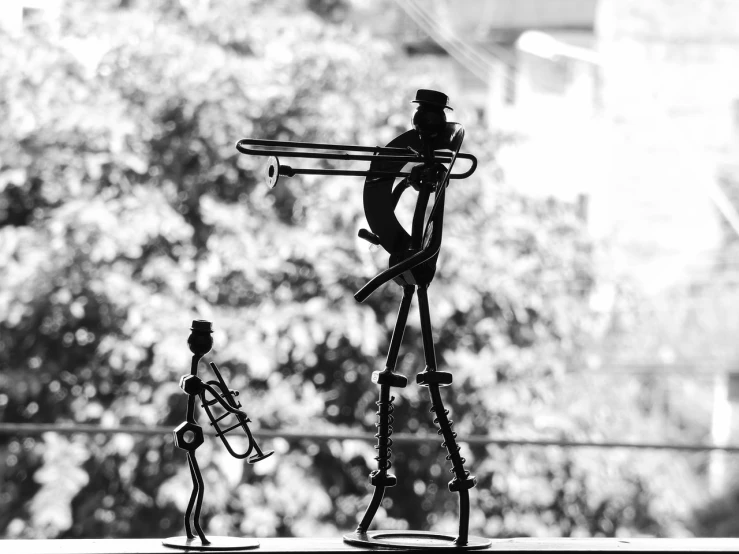 a couple of figurines sitting on top of a window sill, by Sudip Roy, kinetic art, focus on the musicians, b & w, trumpet, band name is tripmachine