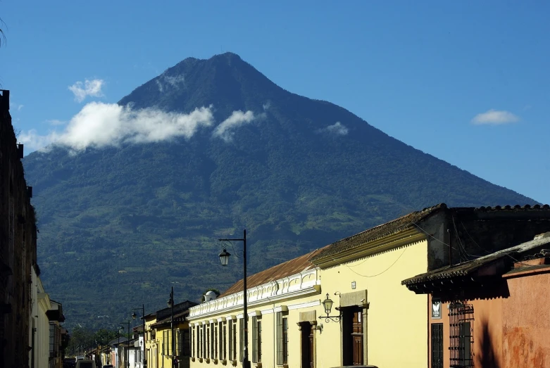 a street with buildings and a mountain in the background, by Juan O'Gorman, flickr, volcano in background, pacal votan, tradition, giant imposing mountain