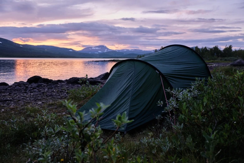 a tent pitched up next to a body of water, by Jóhannes Geir Jónsson, hurufiyya, nice sunset, green and purple, mountain in the background, :: morning