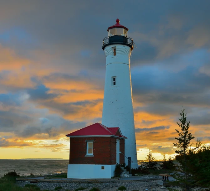 a white and red lighthouse sitting on top of a sandy beach, by Greg Rutkowski, shutterstock, sun rays at sunset, overcast dawn, tyndall rays, built on a small