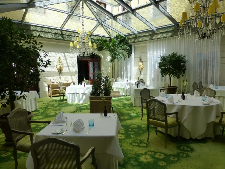 a dining room filled with lots of tables and chairs, by Hugo Heyrman, romantic greenery, glass ceilings, yellow and green scheme, inside white room