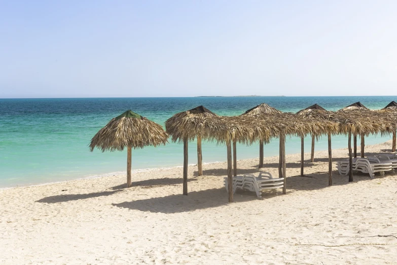 a row of straw umbrellas sitting on top of a sandy beach, a picture, shutterstock, varadero beach, red sea, deserted, usa-sep 20