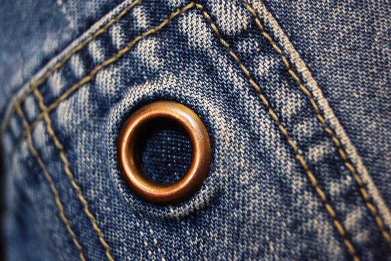 a close up of a button on a pair of jeans, by Alexander Bogen, pexels, renaissance, copper, black round hole, 33mm photo, gold and indigo