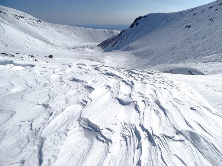 a man riding skis down a snow covered slope, a picture, by Andrei Kolkoutine, les nabis, looking down at a massive crater, vortex river, lots of white cotton, georgic