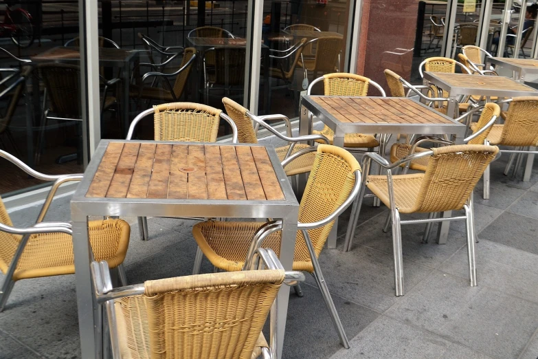 a row of tables and chairs outside of a restaurant, by Joseph Raphael, shutterstock, stainless steel, manhattan, wicker chair, unfinished