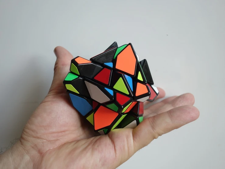 a person holding a rubik cube in their hand, a jigsaw puzzle, inspired by Ernő Rubik, tumblr, cubo-futurism, triangle shards, black 3 d cuboid device, top - side view, diana levin