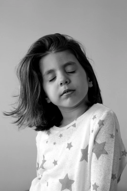a black and white photo of a little girl with her eyes closed, confident relaxed pose, star child, mirka andolfo, her hair flowing down