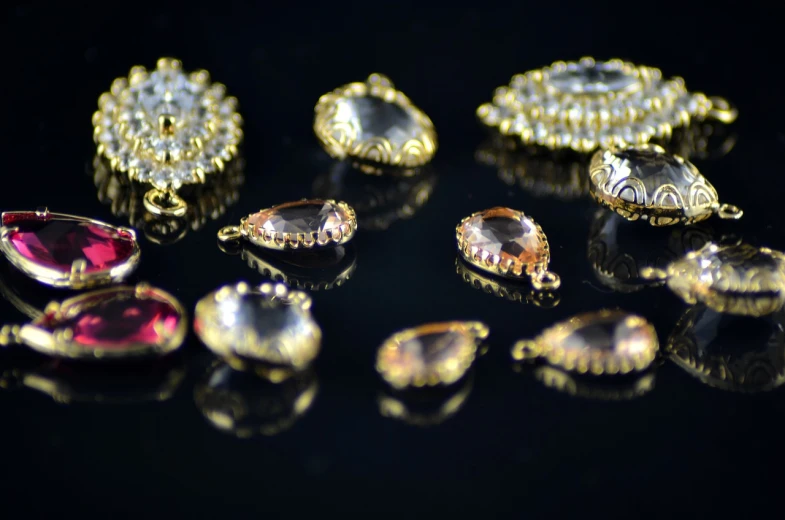 a close up of a bunch of jewelry on a table, by Maksimilijan Vanka, pexels, assemblage, tear drops, inlaid with gold rococo, 18mm, topaz