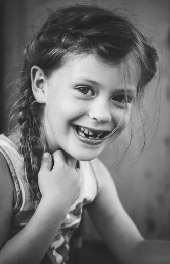 a black and white photo of a little girl smiling, by Jakob Gauermann, pexels contest winner, she has perfect white teeths, girl with plaits, broken teeth, 15081959 21121991 01012000 4k