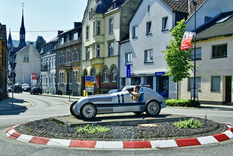 a car that is sitting in the middle of a street, inspired by Otto Meyer-Amden, flickr, art nouveau, at circuit de spa francorchamps, set in ww2 germany, aluminium, detmold charles maurice