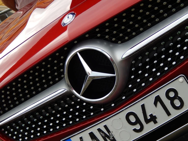 a close up of a mercedes logo on a car, a picture, by Thomas Häfner, pexels, precisionism, red car, photo-realistic maximum detail, photo taken in 2018, detailed zoom photo