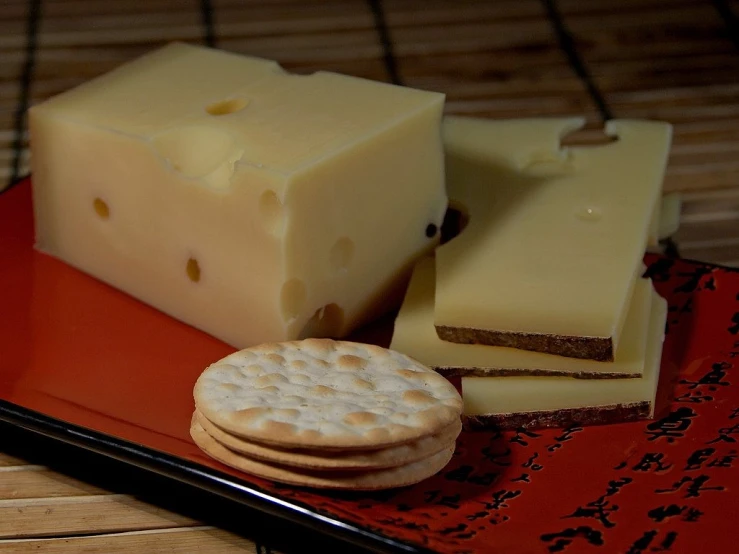 a red plate topped with crackers and cheese, by Dietmar Damerau, flickr, sake, made of swiss cheese wheels, rectangular, shiny crisp finish