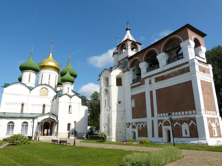 a large white and brown building with green domes, a picture, by Serhii Vasylkivsky, shutterstock, monastery, summer season, elegant walkways between towers, cathedral of sun