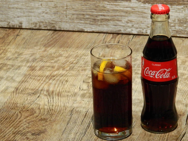 a bottle and a glass of coke on a table, on a wooden table, 15081959 21121991 01012000 4k, high quality product image”