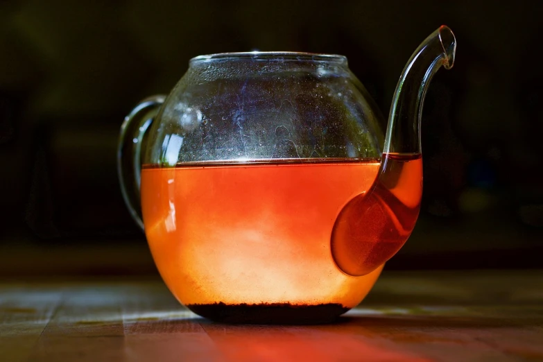 a tea pot sitting on top of a wooden table, by Jan Rustem, pexels, red and orange glow, light through glass, jamaica, closeup photo