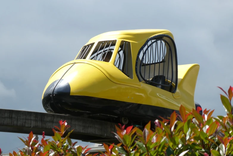 a close up of a yellow train on a track, by Edward Corbett, flickr, retrofuturism, flying car, theme park, fiberglass, lush garden spaceship