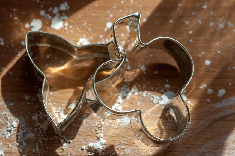 a couple of cookie cutters sitting on top of a wooden table, a still life, tom and jerry, gelatine silver process, close-up product photo, metal neck rings