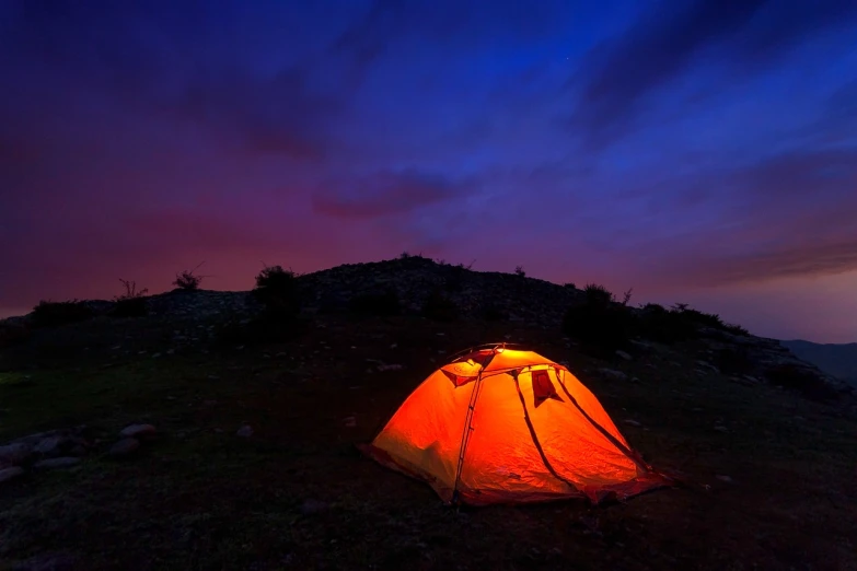 a tent lit up at night on top of a hill, a picture, istock, red cloud light, outdoor photo, strong blue and orange colors