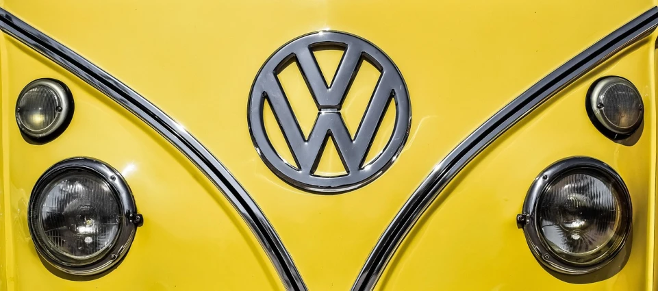 a close up of the front of a yellow vw bus, by Juergen von Huendeberg, emblem, full color, highly polished, shot on 85mm