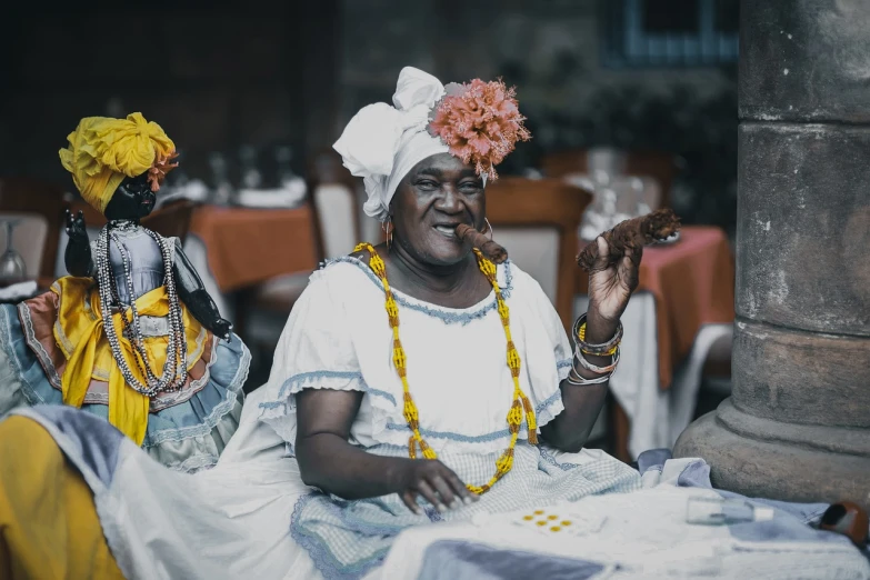 a couple of women sitting next to each other, a colorized photo, inspired by Candido Bido, pexels, afrofuturism, dressed as a pastry chef, cuban setting, papa legba, holy ceremony