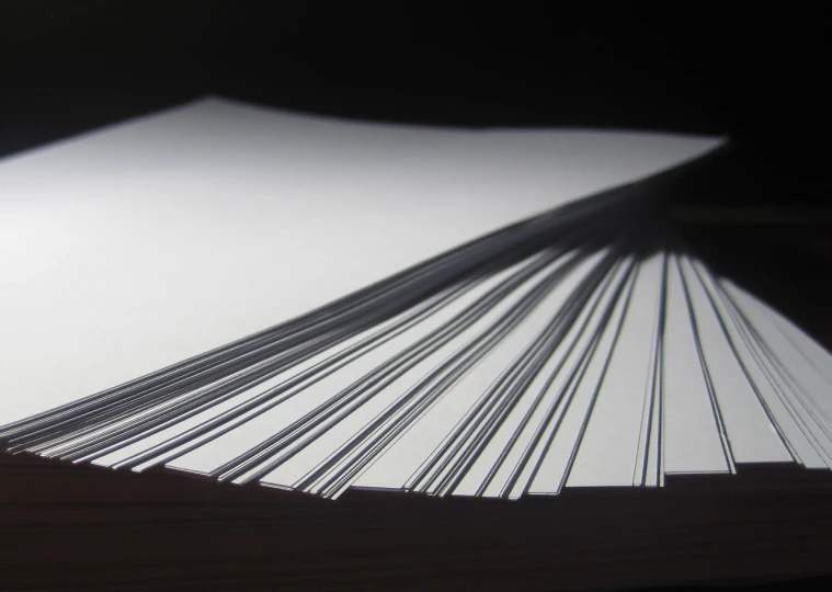 a stack of papers sitting on top of a table, by Andrei Kolkoutine, extremely sharp lines, backlit, detailed - i, blades