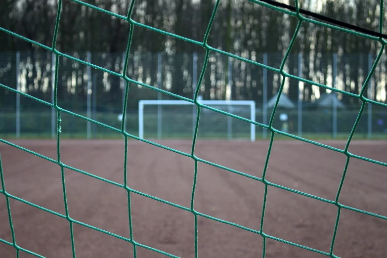 a view of a baseball field through a fence, a picture, by Thomas Häfner, shutterstock, on a soccer field, mesh structure, forest green, dry ground