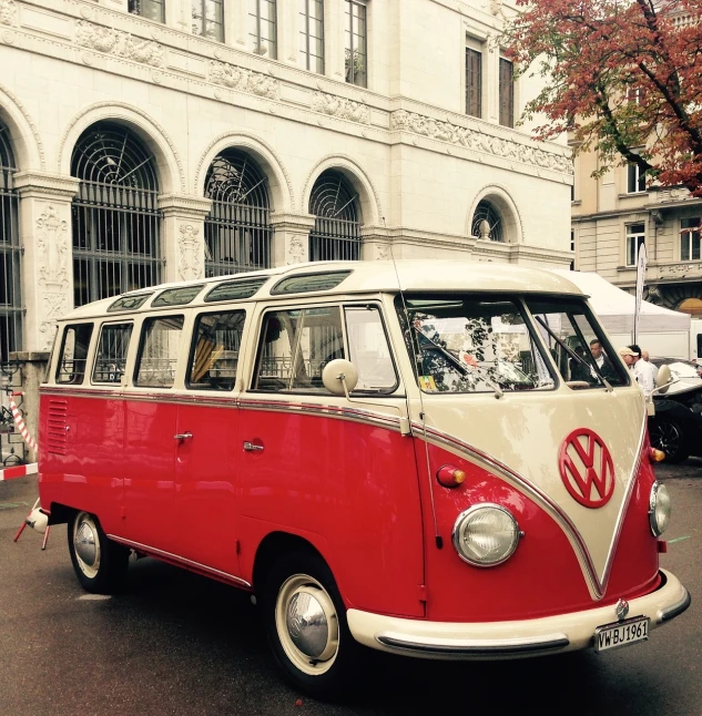 a red and white vw bus parked in front of a building, a photo, bautiful, vintage car, autumn season, vienna city