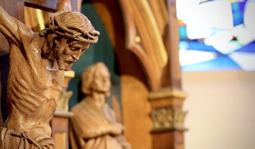 a close up of a statue of jesus on a cross, a statue, by Robbie Trevino, in front of a carved screen, with depth of field, in this church interior, wesley kimler