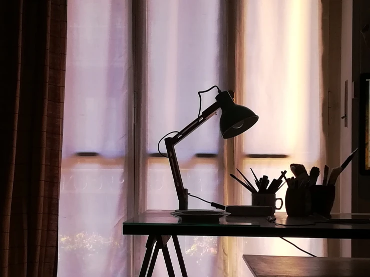 a lamp sitting on top of a desk next to a window, by Andrei Kolkoutine, pexels, detailed silhouette, cinematic shot!, art workstation, studyng in bedroom