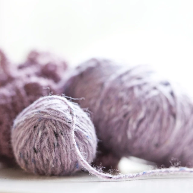 a pile of yarn sitting on top of a table, a portrait, inspired by Shūbun Tenshō, unsplash, light purple, tweed colour scheme, dof 1. 3, unfocus