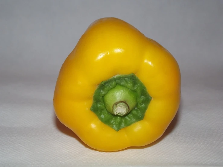 a yellow bell pepper sitting on a white surface, a picture, by Jan Rustem, flickr, dada, cone shaped, jpeg artifact, colored accurately, bottom - view