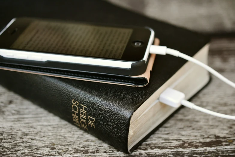 a cell phone sitting on top of a book, a portrait, bible, iphone wallpaper, battery, portlet photo