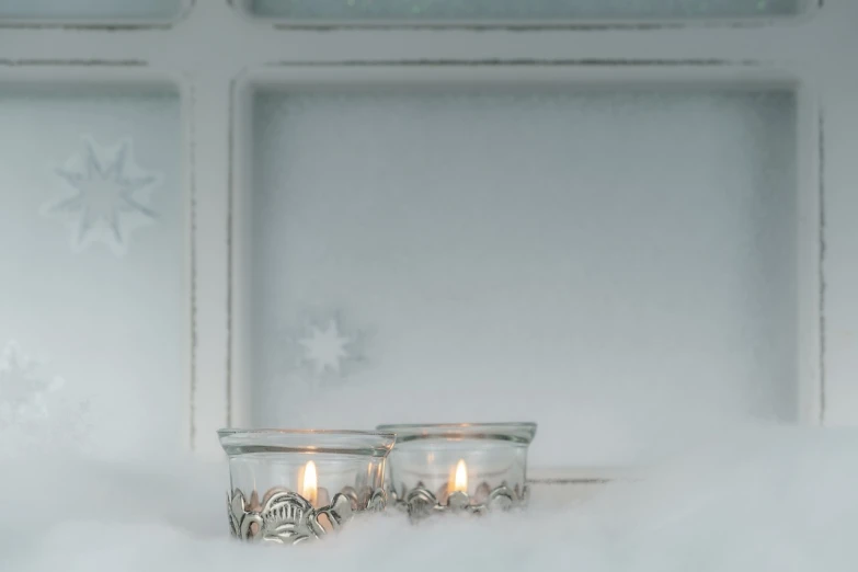 two candles that are sitting in the snow, clear glass wall, detailed carved ornaments, light frame, miniature product photo