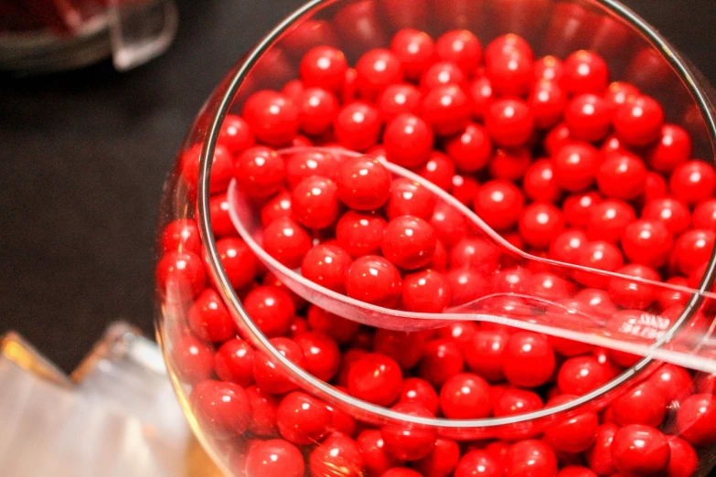 a glass filled with red candy sitting on top of a table, metaballs, gourmet, hundreds of them, inputs