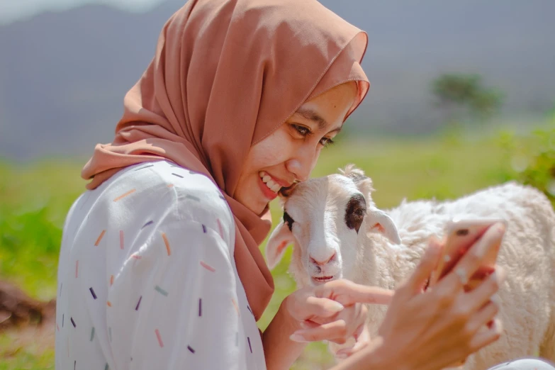 a woman in a hijab petting a sheep, a picture, by Basuki Abdullah, shutterstock, happy friend, portrait shot 8 k, photo of young woman, 🐋 as 🐘 as 🤖 as 👽 as 🐳