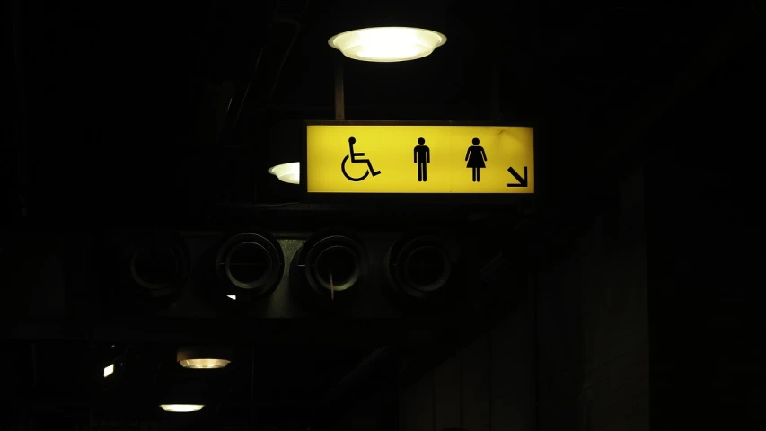 a bathroom sign is lit up in the dark, a photo, excessivism, wheelchair, terminal, disco pictoplasma, old signs