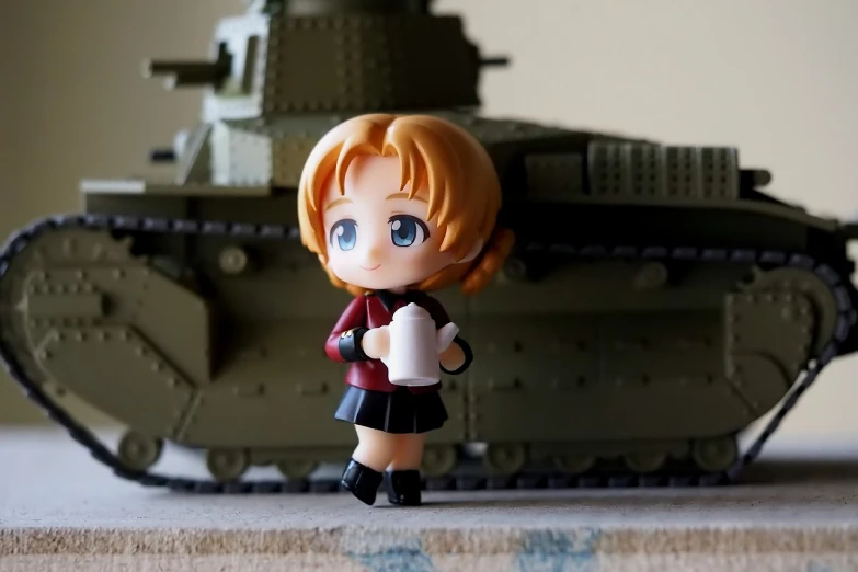 a close up of a toy with a tank in the background, a picture, inspired by Li Chevalier, flickr, figuration libre, k-on!, tiny waist, shot with sigma f / 4. 2, ddlc