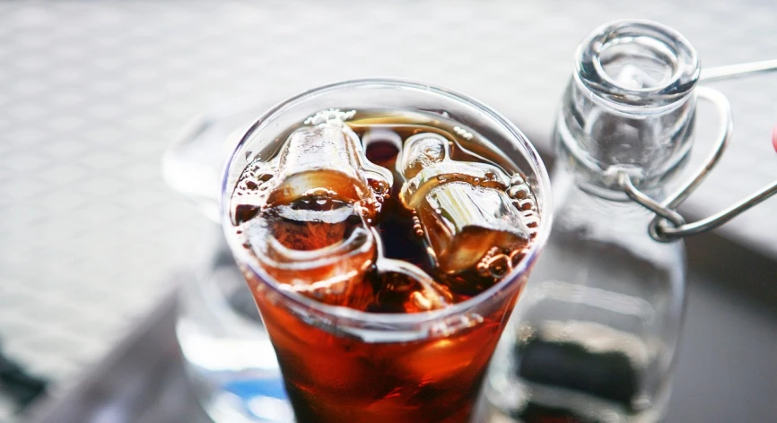 a glass of soda sitting on top of a table, by Lee Loughridge, pexels, arabica style, iced tea glass, zoomed in, aaaaaaaaaaaaaaaaaaaaaa