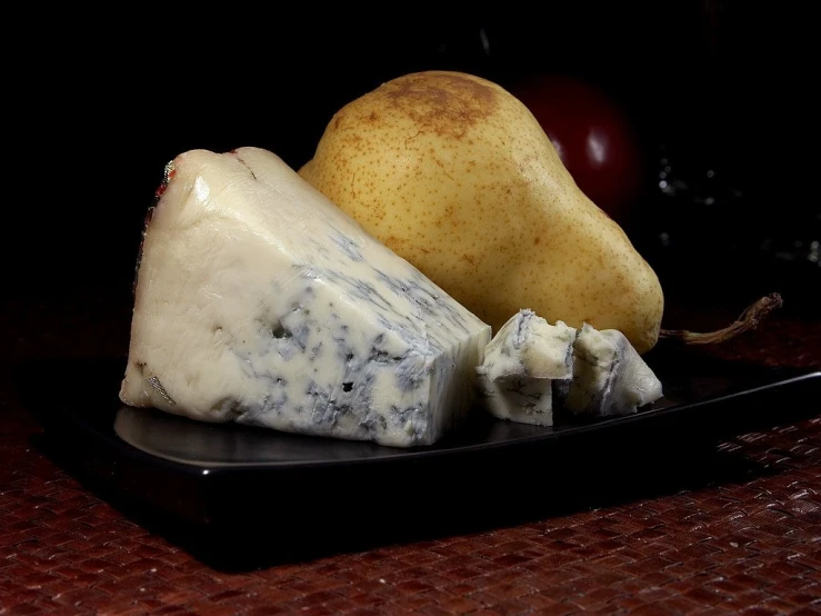 a black plate topped with cheese and pears, a still life, by Paul Davis, pixabay, dipped in polished blue ceramic, blue fur with white spots, made of cheese, pale bluish skin