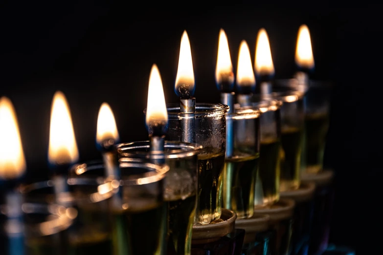 a row of lit candles sitting next to each other, by Micha Klein, hebrew, full of greenish liquid, istock, bright glowing instruments