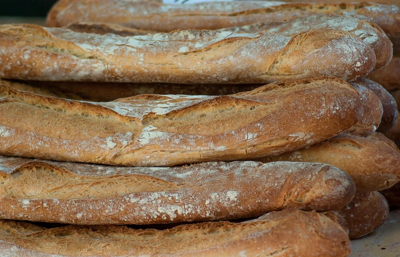a pile of bread sitting on top of a table, inspired by Normand Baker, pexels, baking french baguette, wikimedia, close up to a skinny, in a row
