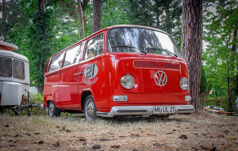 a red vw bus parked next to a trailer, by Richard Carline, pixabay contest winner, photorealism, full face frontal centred, kombi, epic. 1 0 0 mm, 🕹️ 😎 🔫 🤖 🚬