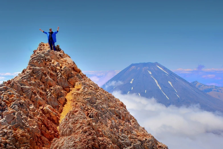 a man standing on top of a rocky mountain, a tilt shift photo, by Juan O'Gorman, shutterstock, fantastic realism, volcano in background, chile, standing triumphant and proud, award-winning photo uhd