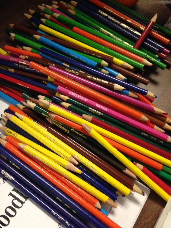 a pile of colored pencils sitting on top of a table, by senior artist, photorealism. trending on flickr, art station”