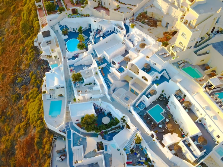 an aerial view of a resort with a swimming pool, a tilt shift photo, in santorini island, white wall complex, crazy detailed and complex, during sunrise