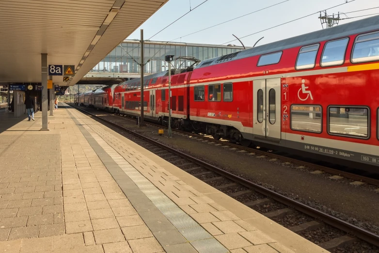 a red and silver train pulling into a train station, a picture, by Karl Völker, shutterstock, img _ 9 7 5. raw, accessible for the disabled, taken on iphone 14 pro, hannover