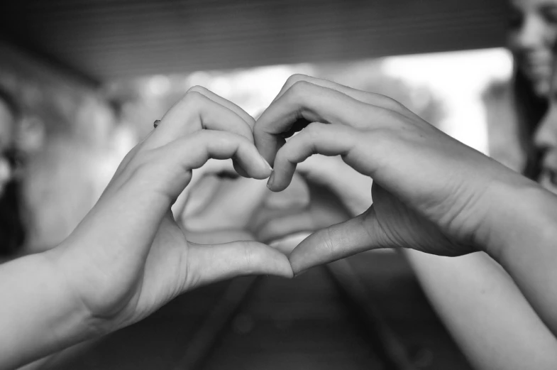 two people making a heart with their hands, a black and white photo, by Lilia Alvarado, pexels, rails, stock photo, low quality photo, very realistic