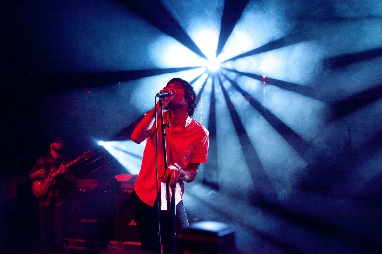 a man that is standing in front of a microphone, by Fernando Gerassi, jonny greenwood, advanced stage lighting, chrysanthemum eos-1d, high red lights