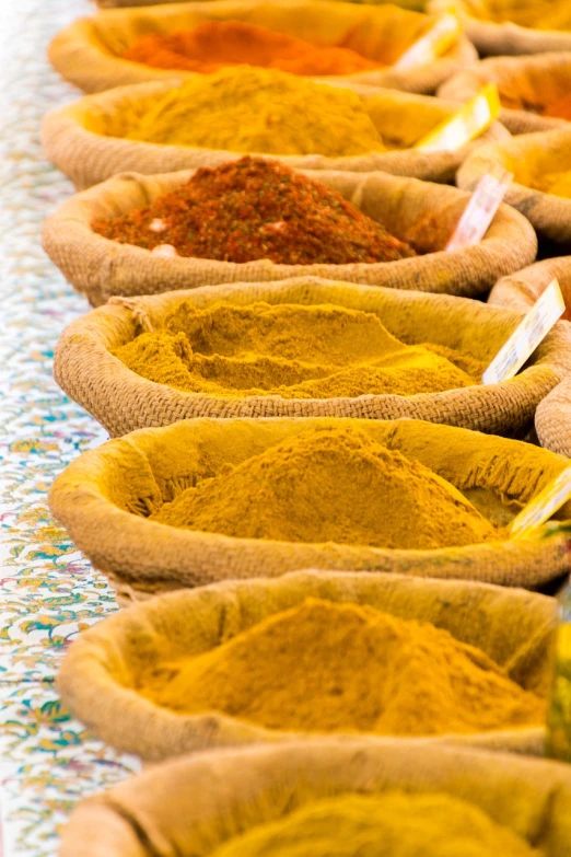 a row of bowls filled with different types of spices, a photo, inspired by John Steuart Curry, renaissance, yellow colors, the vibrant echoes of the market, high quality product image”